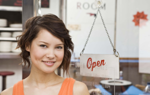Woman smiling by open sign at diner